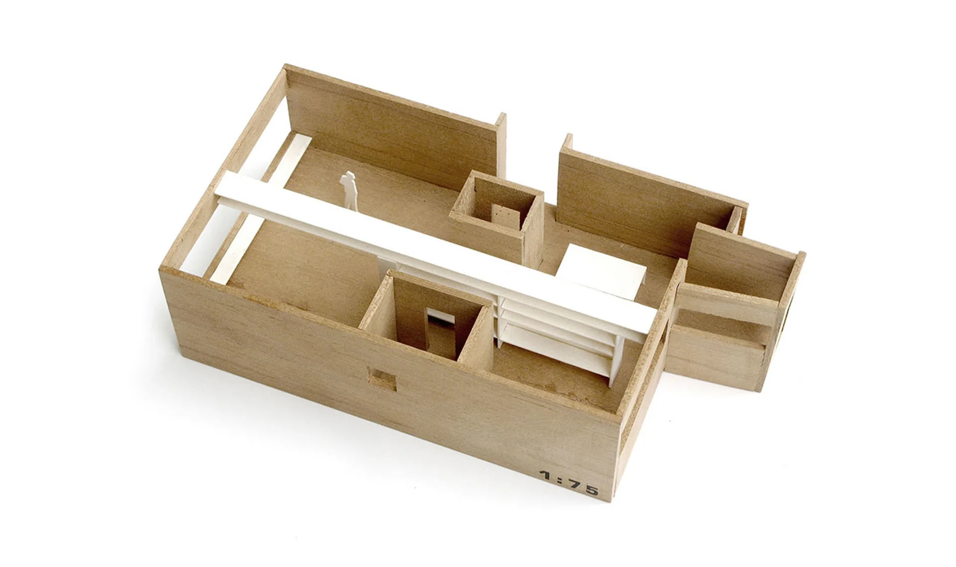 An overhead shot of a wooden architectural scale model at one to seventy-five scale, featuring partition walls and a long white shelving element.