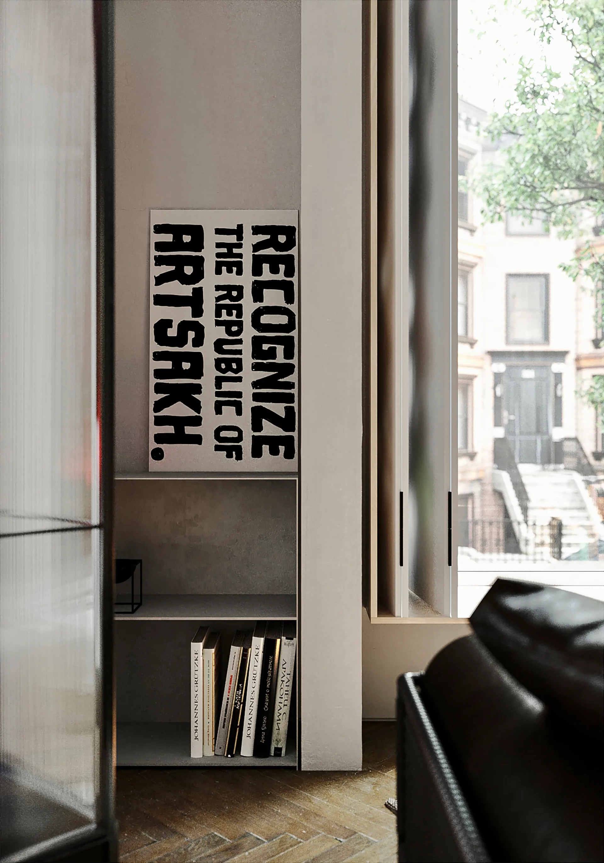 A gray metal shelving unit holding books sits next to a window, with a black-and-white typographic poster leaning against the wall above it.