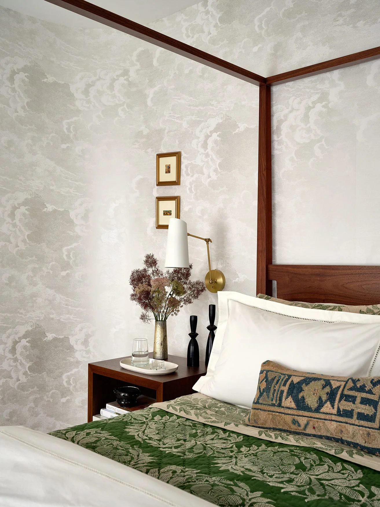 A bedroom corner features a wooden canopy bed with a green patterned quilt, a matching nightstand, and grey cloud wallpaper.