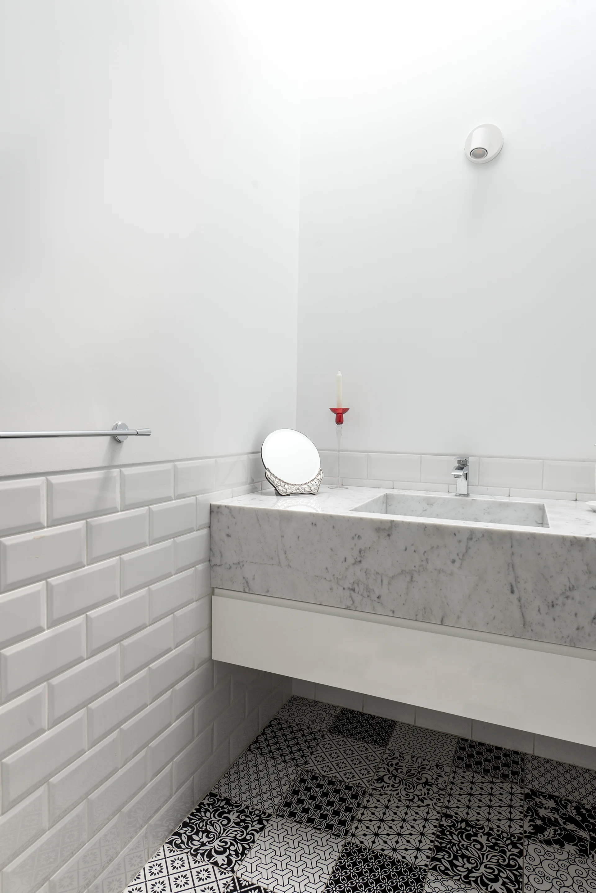 A modern bathroom featuring a thick marble floating vanity with an integrated sink, white subway wall tiles, and patterned black and white floor tiles.