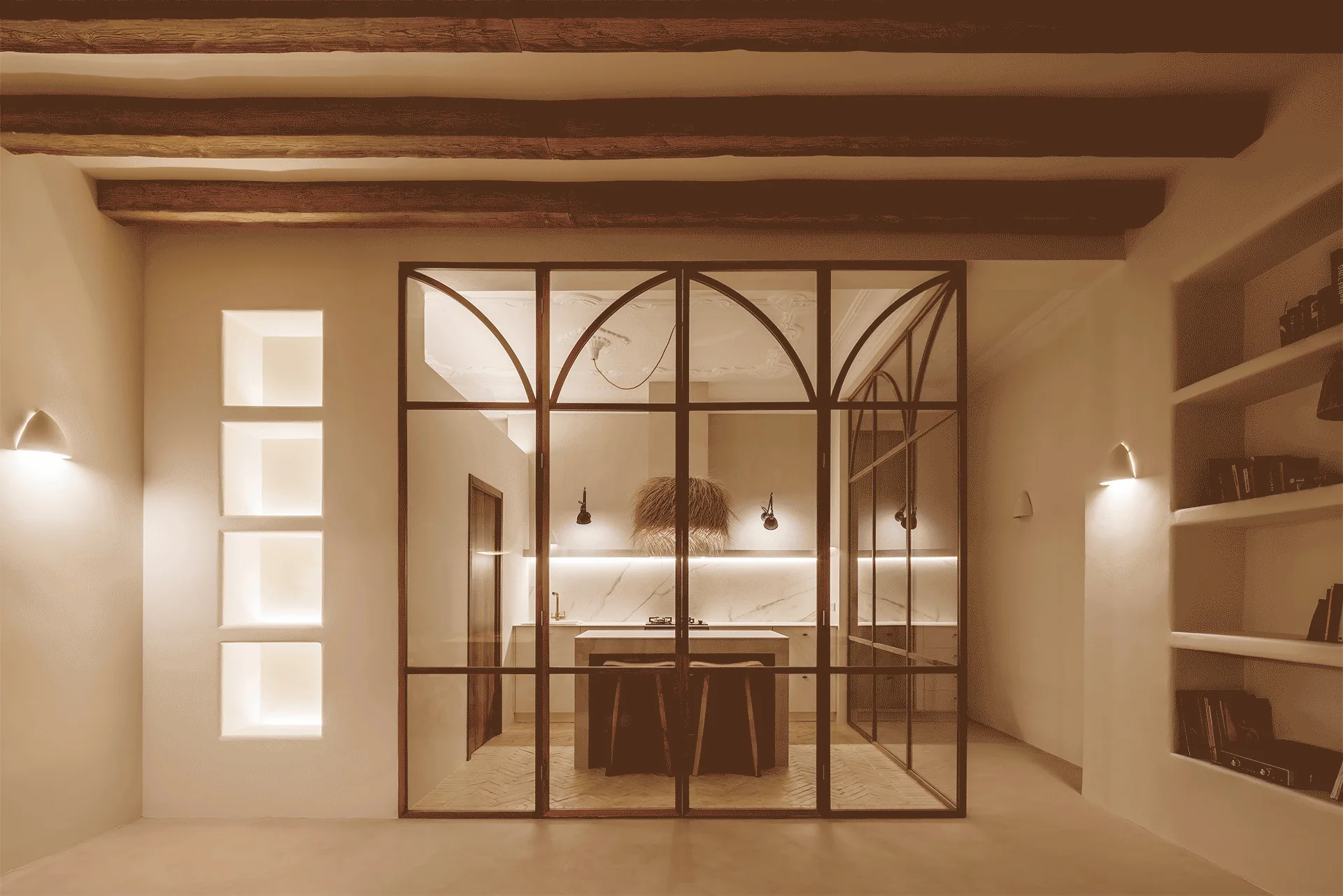 A warm beige kitchen is seen through a black arched metal and glass partition, featuring exposed wooden ceiling beams and illuminated wall niches.