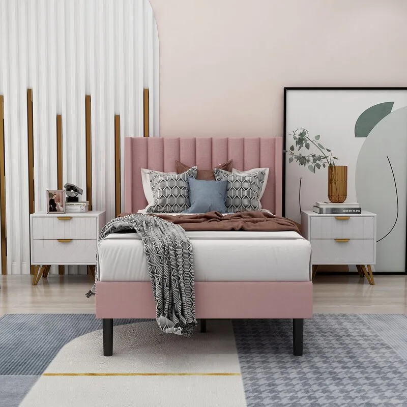 A modern bedroom features a pink upholstered bed with a channeled headboard, flanked by white two-drawer nightstands on a geometric patterned rug.
