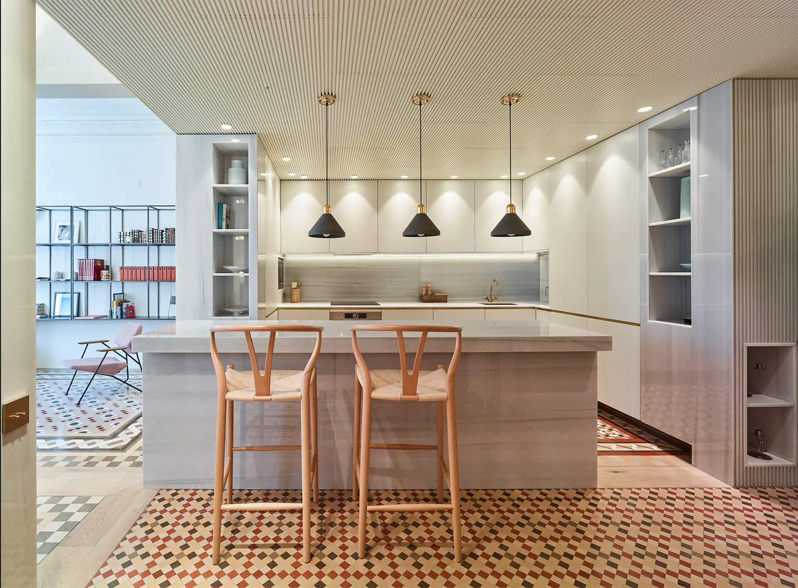 A kitchen featuring a stone island with two wooden bar stools under black pendant lights beneath a textured, slatted wood ceiling.