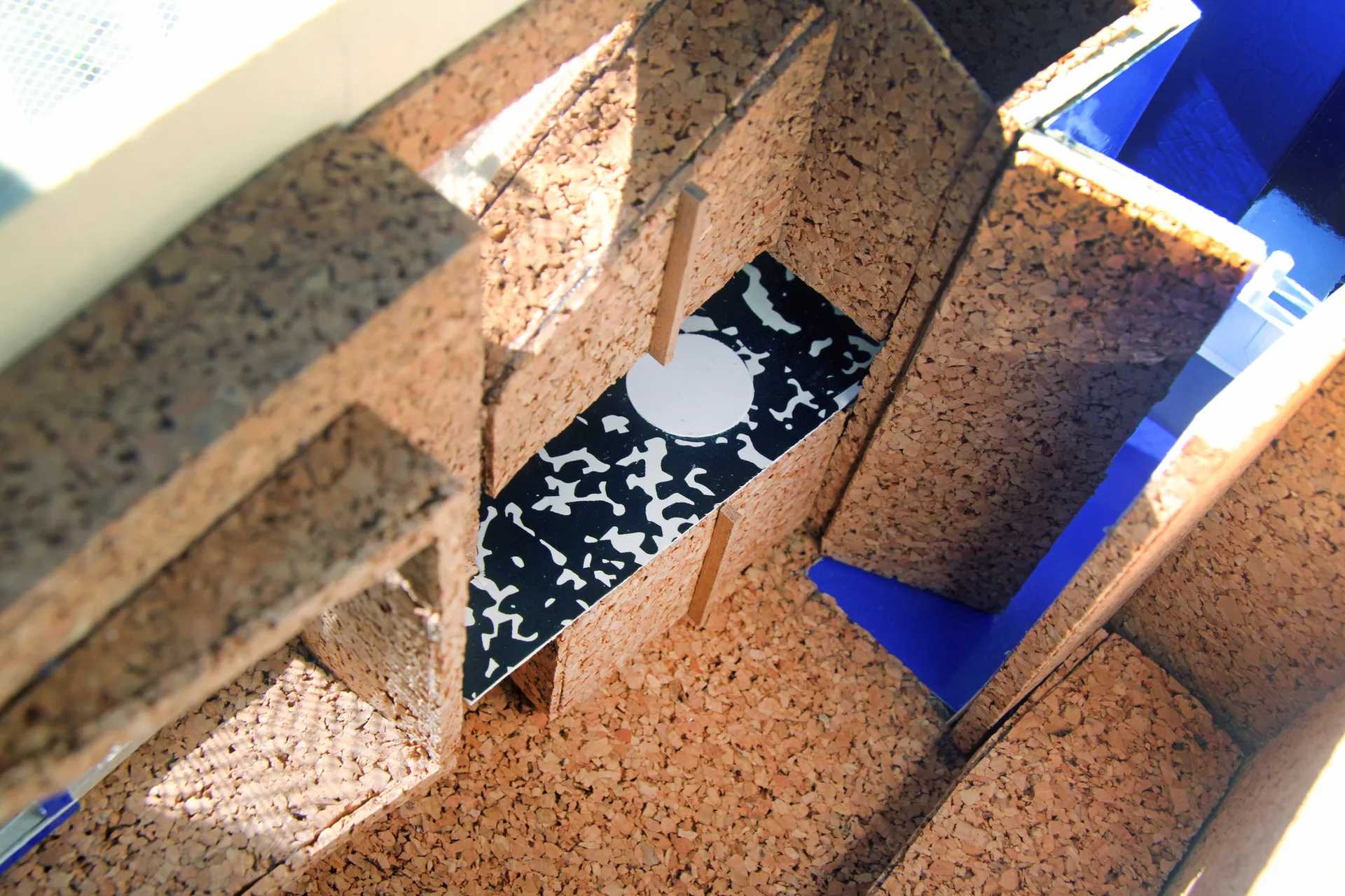 An architectural model of a staircase featuring textured brown cork panels and a black-and-white speckled pattern insert.
