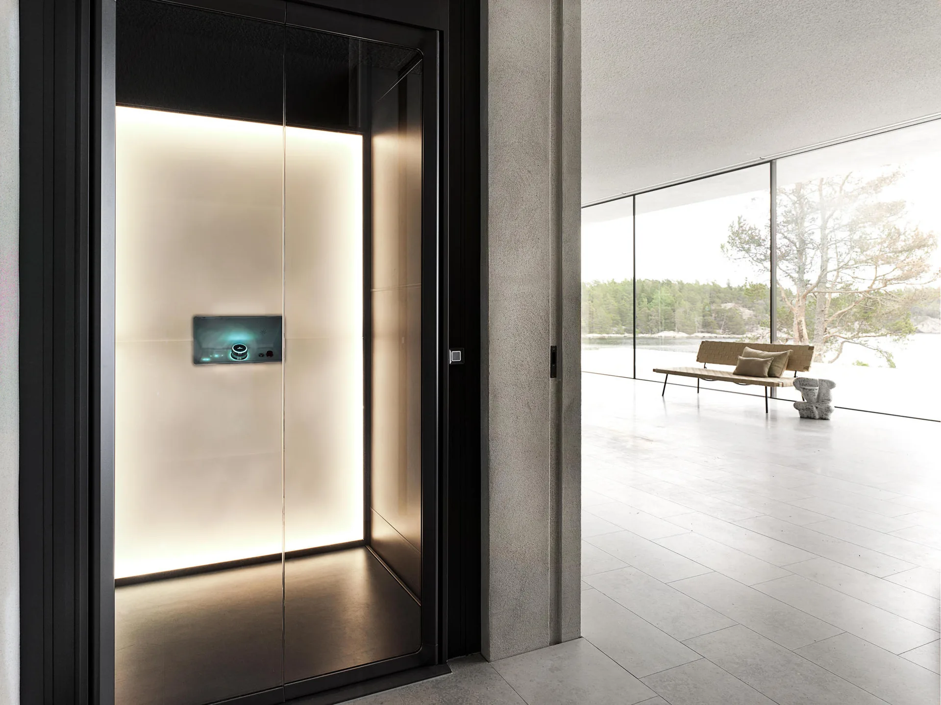 A modern minimalist home interior featuring a black-framed elevator with a backlit glass wall next to a large window overlooking trees.