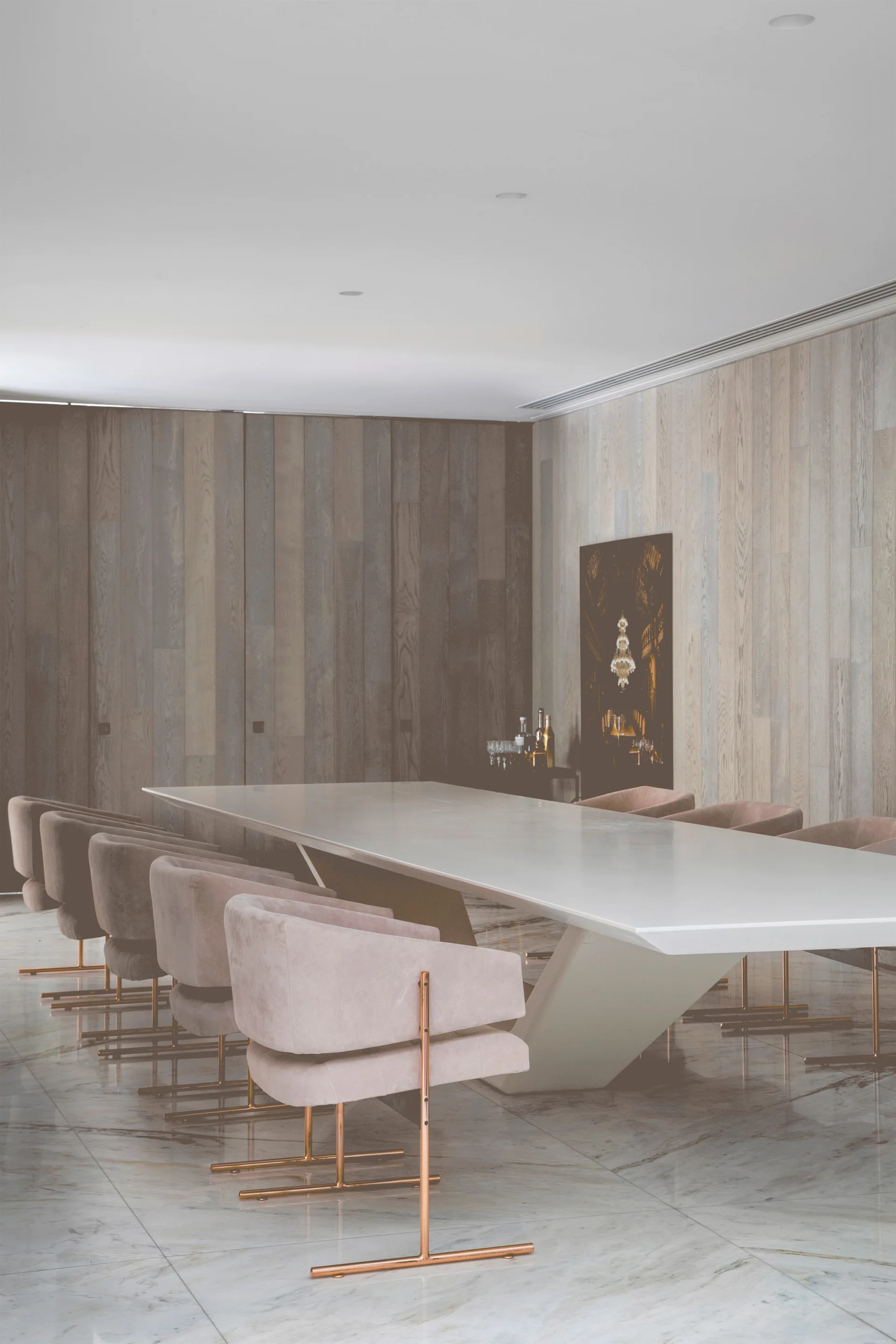 Modern dining room featuring a long white sculptural table, upholstered chairs with copper frames, and vertical wood paneled walls.