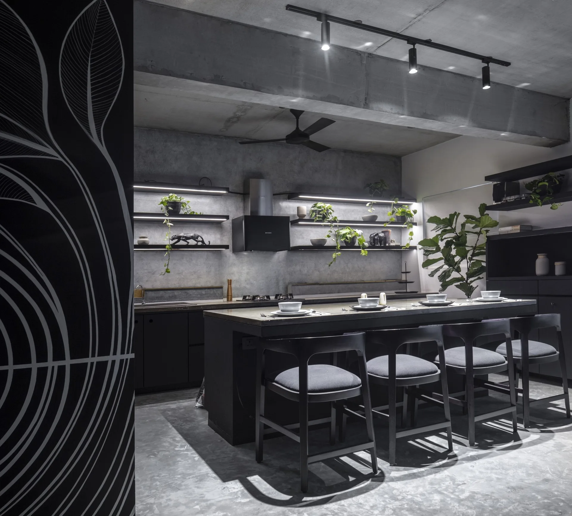 A dark industrial kitchen featuring a concrete island with bar stools, exposed concrete walls, and floating wooden shelves with integrated LED strip lighting.