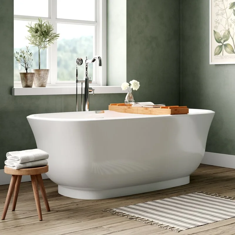 A white freestanding bathtub sits on a wood floor against forest green walls under a bright window.