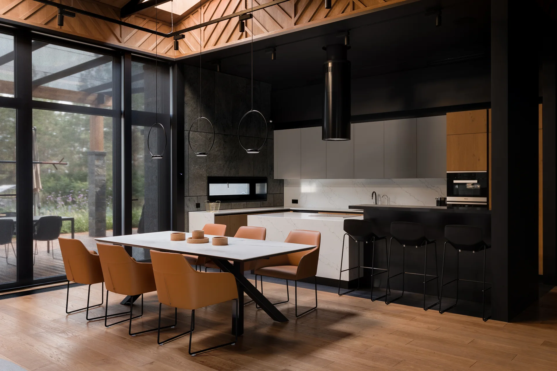 An open-concept kitchen and dining area features orange leather chairs around a white table, a marble island, and a geometric wood ceiling.