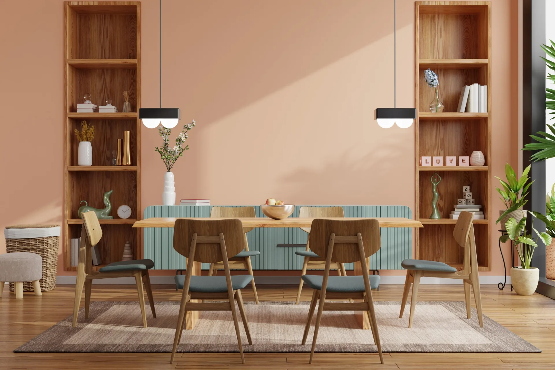 A dining room features a wooden table and chairs, a teal sideboard, and symmetrical built-in wood bookshelves against a salmon pink wall.