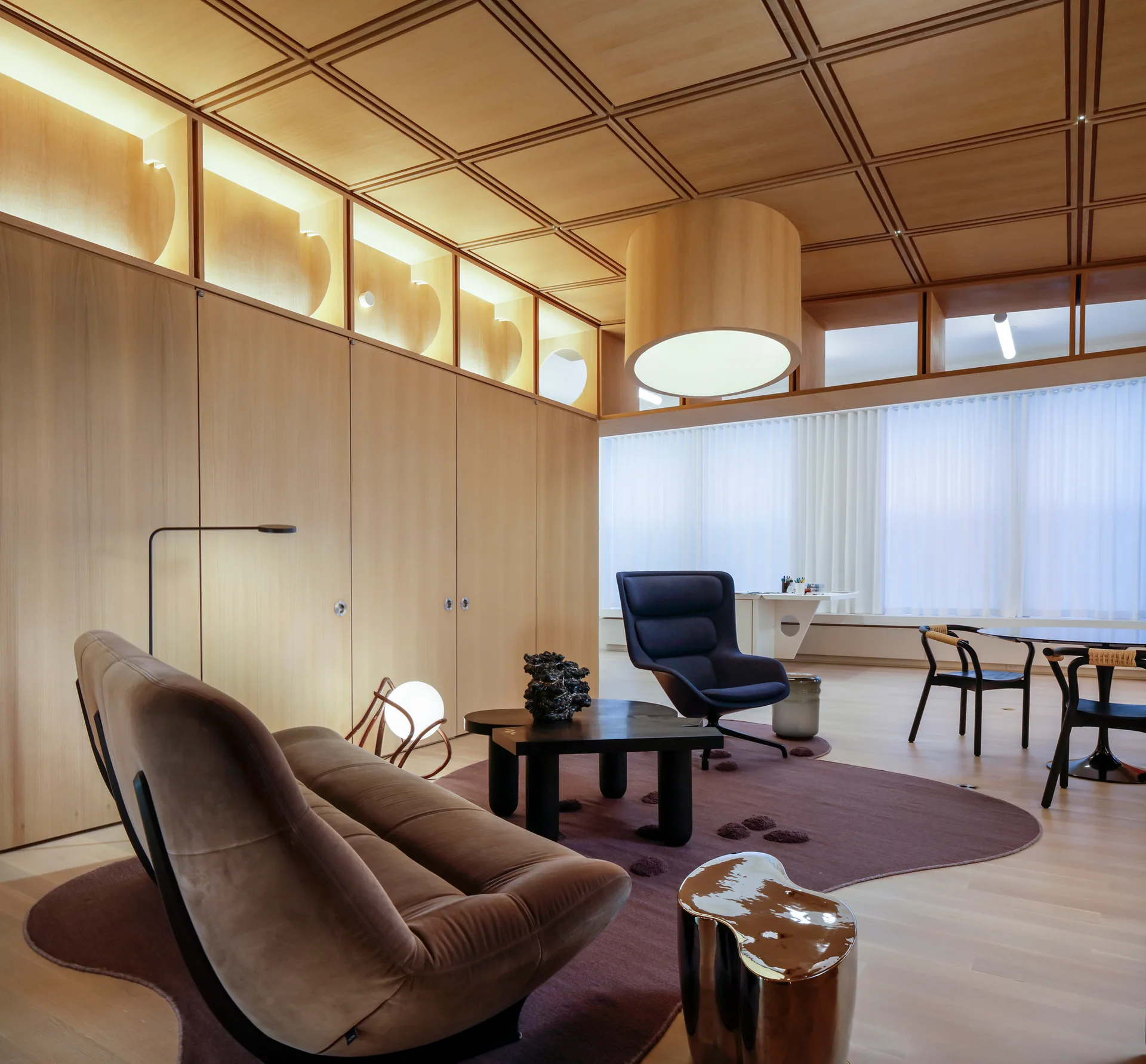 A contemporary living room featuring a grid-patterned wooden ceiling, wood-paneled walls, a low-profile sofa, and an irregular plum rug.
