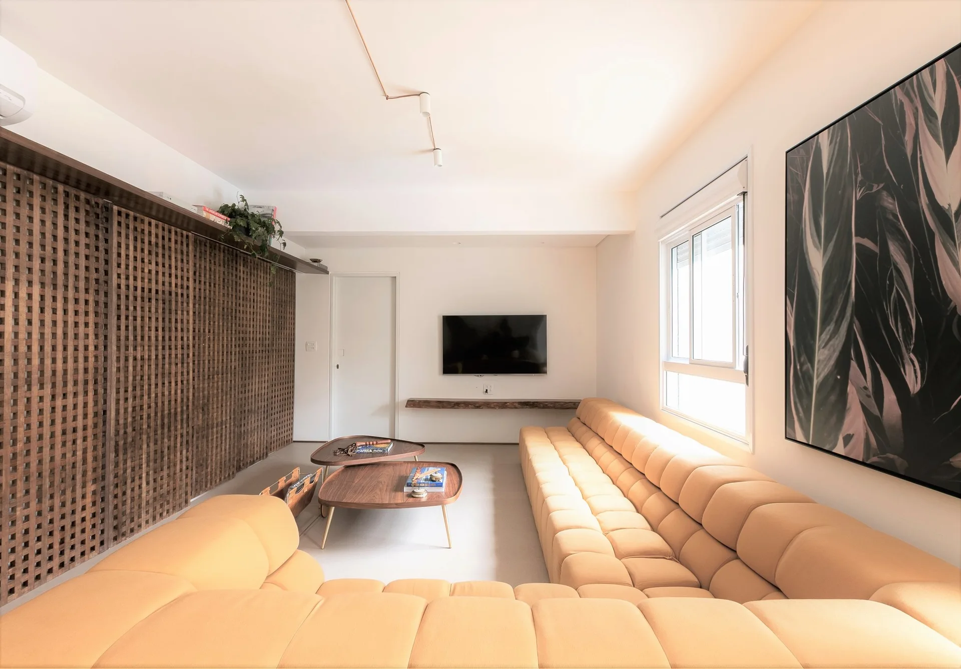 A modern living room featuring a tan modular sectional sofa, nesting wood coffee tables, and a large floor-to-ceiling wooden lattice partition screen.