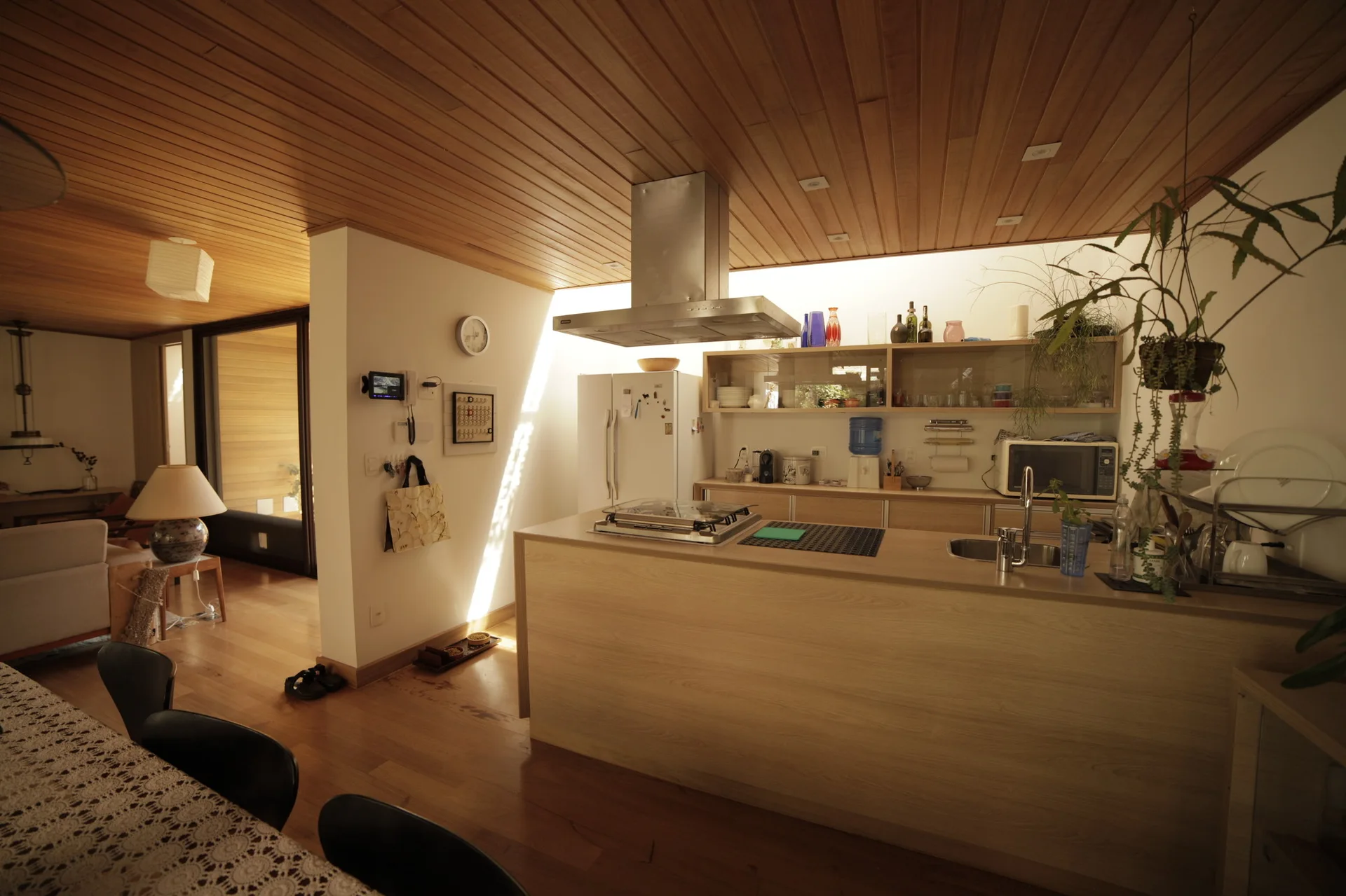 An open kitchen featuring a light wood island, a stainless steel range hood, and a ceiling covered in horizontal wood planks.