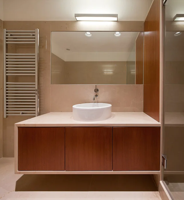 A modern bathroom features a floating wood vanity with a white vessel sink, a large rectangular mirror, and a wall-mounted chrome towel warmer.