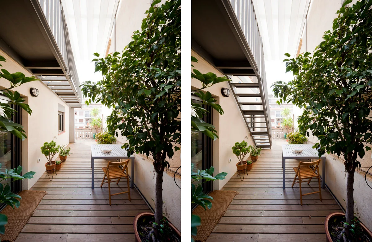 A narrow outdoor terrace features warm wood plank decking, potted green plants, a metal dining table with a wooden chair, and an overhead metal staircase.