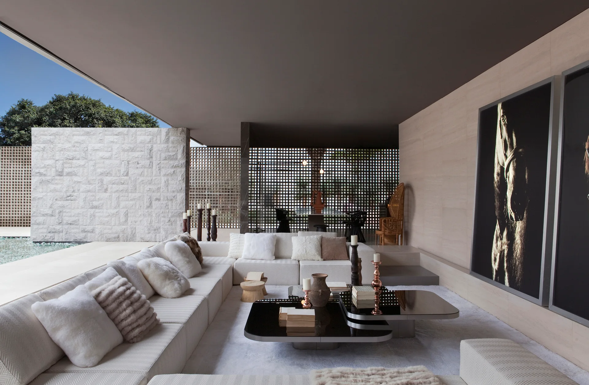 A cream sectional sofa with textured pillows surrounds low-profile black coffee tables in an open-concept living space with a dark ceiling.