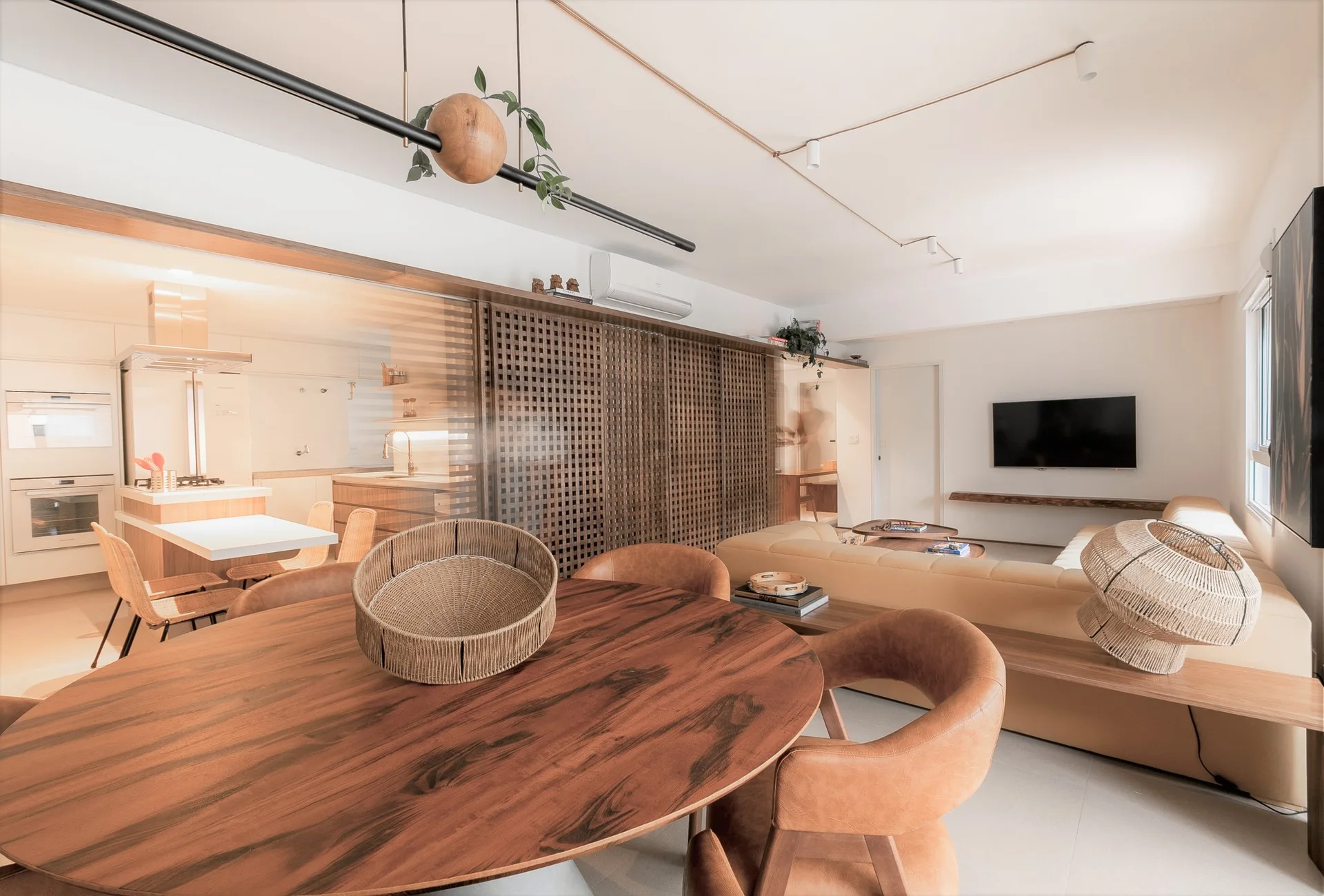 An open-concept living area featuring a round wooden dining table, tan leather chairs, a beige sofa, and a sliding wood lattice partition screen.