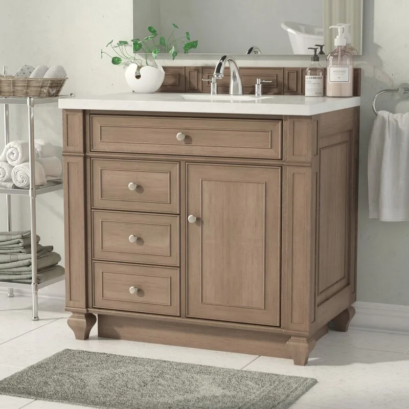 A wooden bathroom vanity with a white countertop and chrome faucet sits next to a metal shelving unit stocked with folded towels.