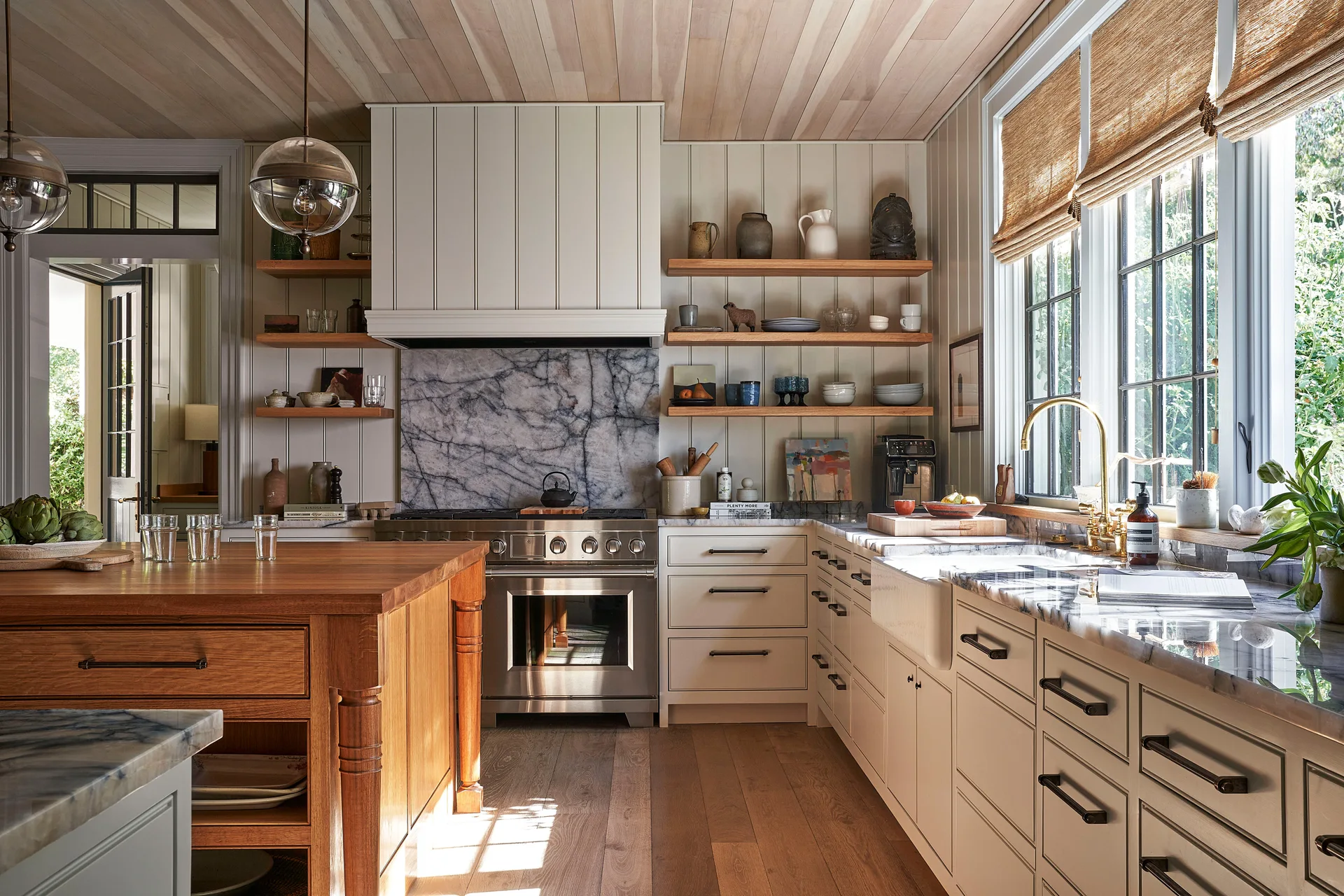 A warm kitchen features a wood plank ceiling, matching wood island, marble slab backsplash, shaker cabinets, and open shelves.