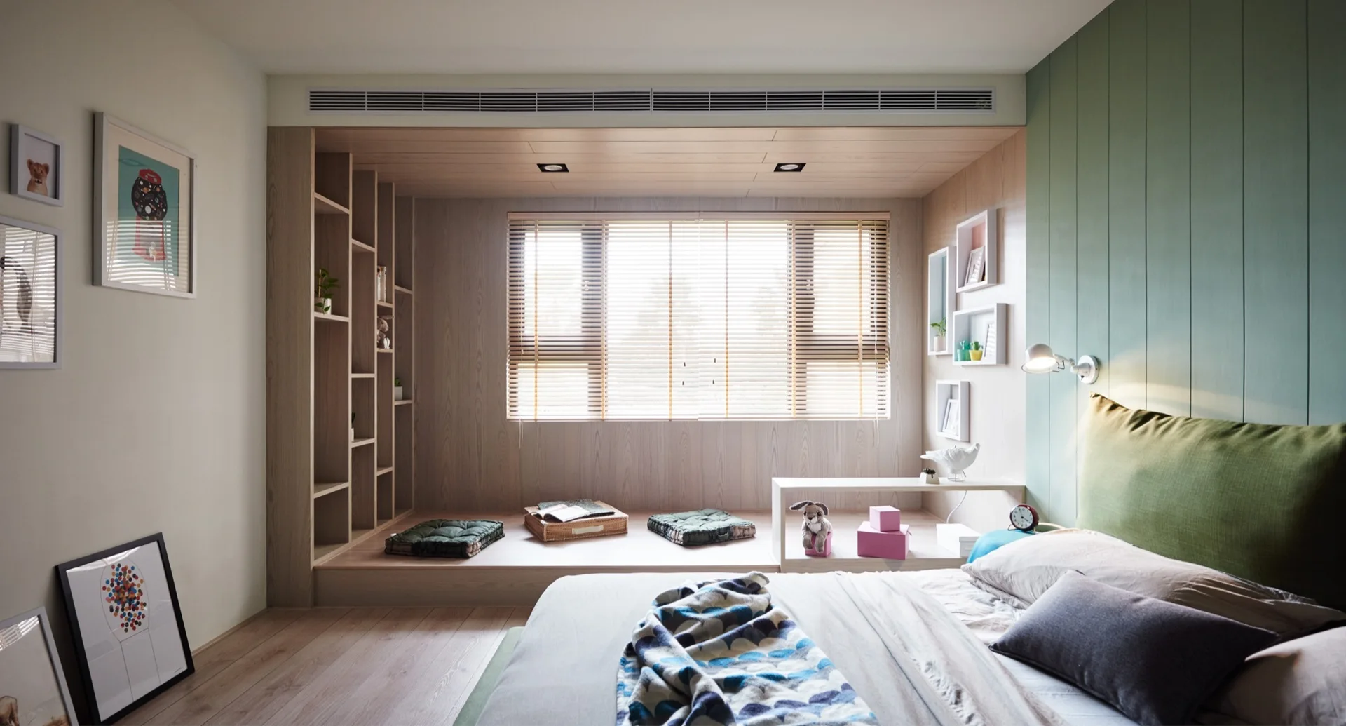 A bedroom features a bed with a sage green paneled wall beside a raised wooden platform seating area with built-in bookshelves.
