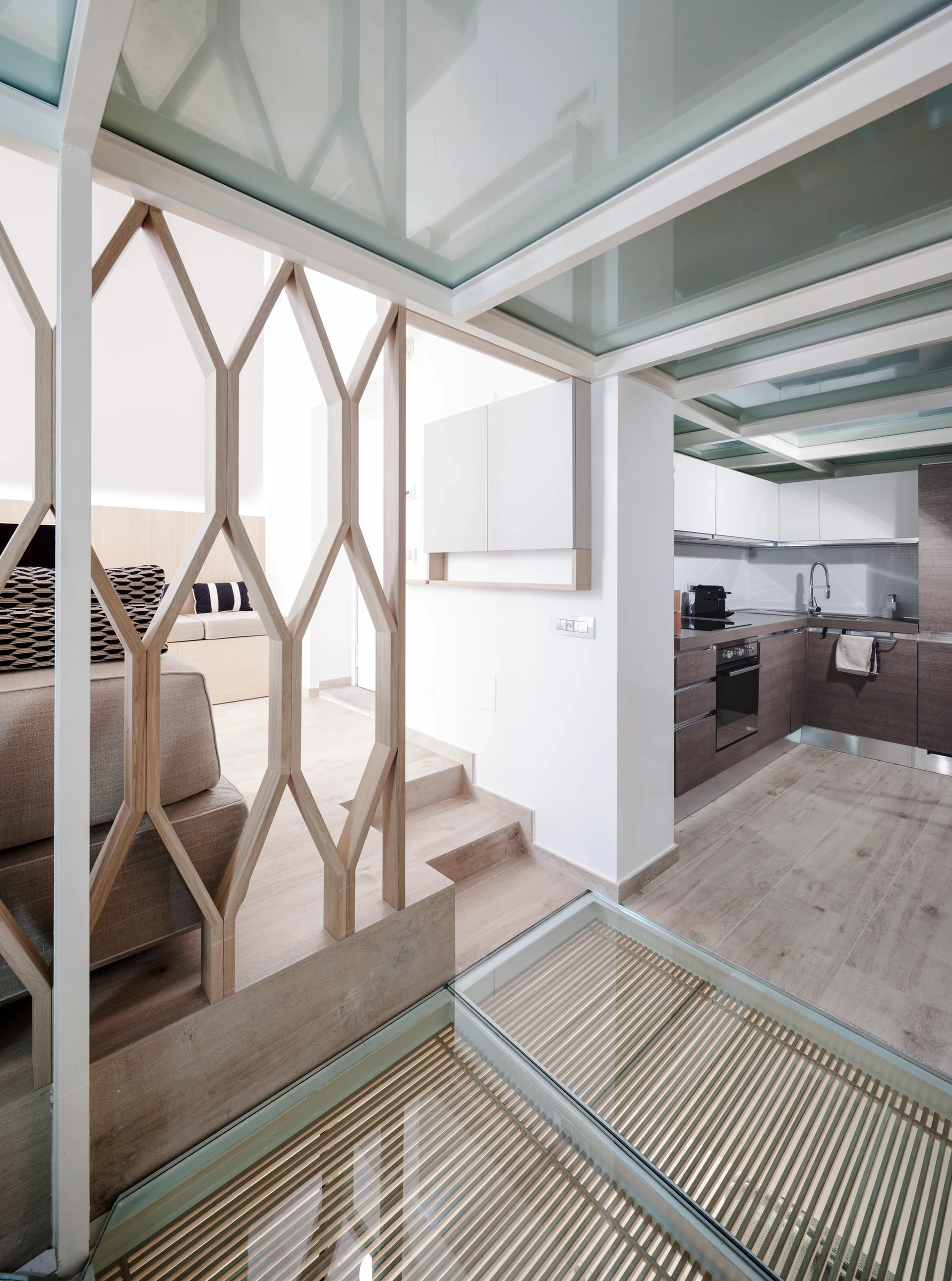 A modern multi-level home interior featuring a wood lattice partition screen, a glass floor with wooden slats, and a kitchen.