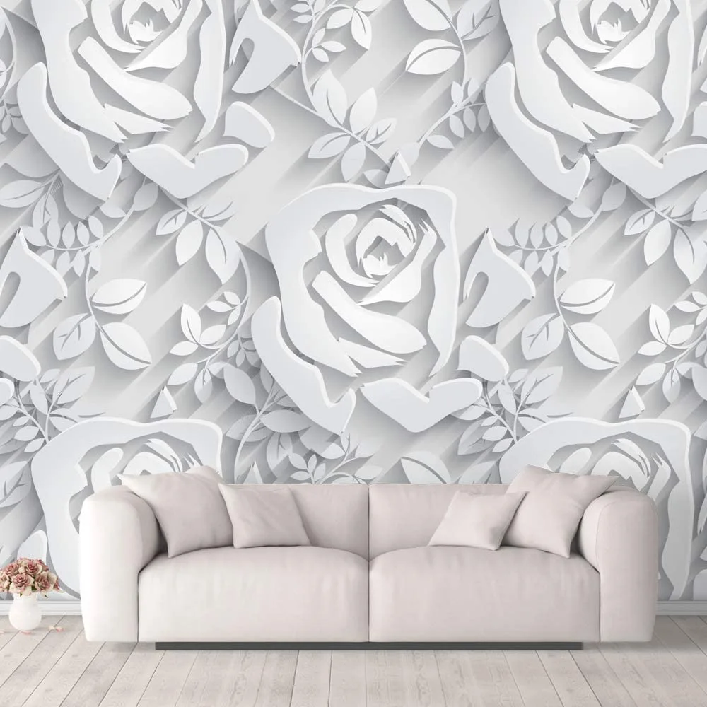 A minimalist off-white sofa stands against a white accent wall featuring a large three-dimensional embossed rose pattern.