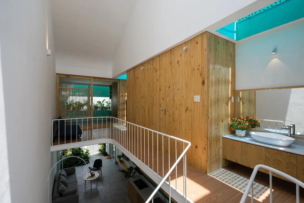 A modern loft landing features a natural wood-clad wall, a floating vanity with a vessel sink, and a white railing overlooking a lower-level living room.