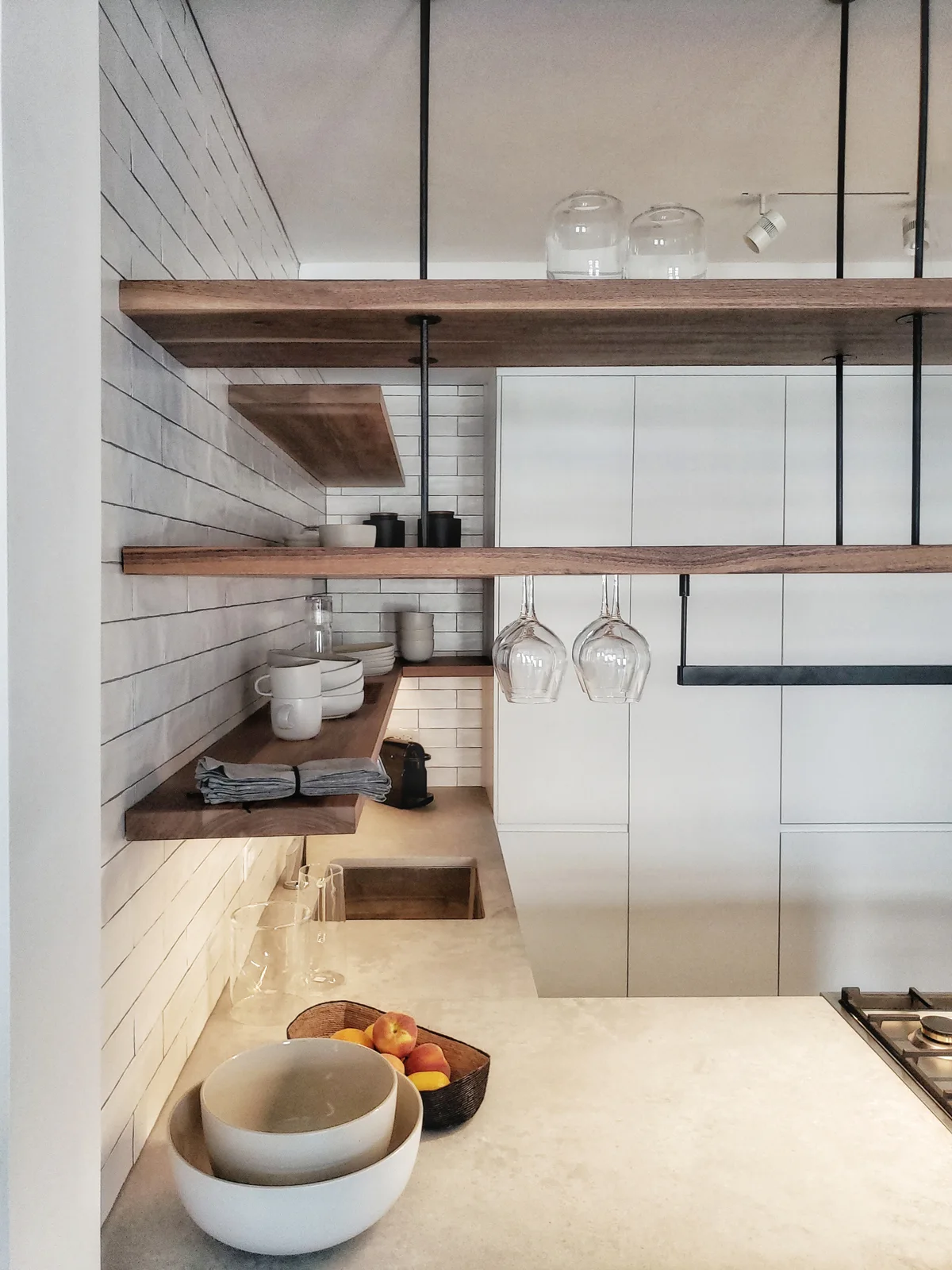 A modern kitchen with suspended wood shelves, a white subway tile backsplash, and stone-like countertops.