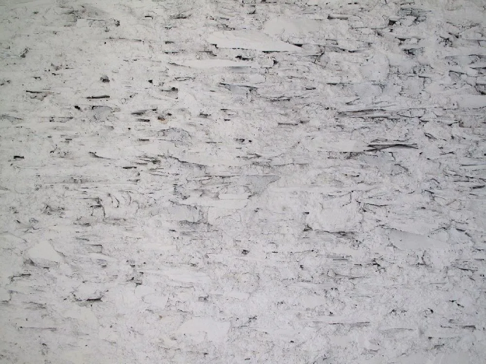A detailed close-up of a rustic stone wall with a heavily textured, whitewashed matte finish.