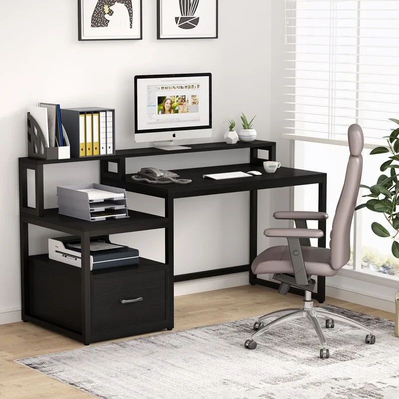 A black metal computer desk with tiered shelving and a printer shelf stands next to a grey ergonomic office chair on a distressed rug.