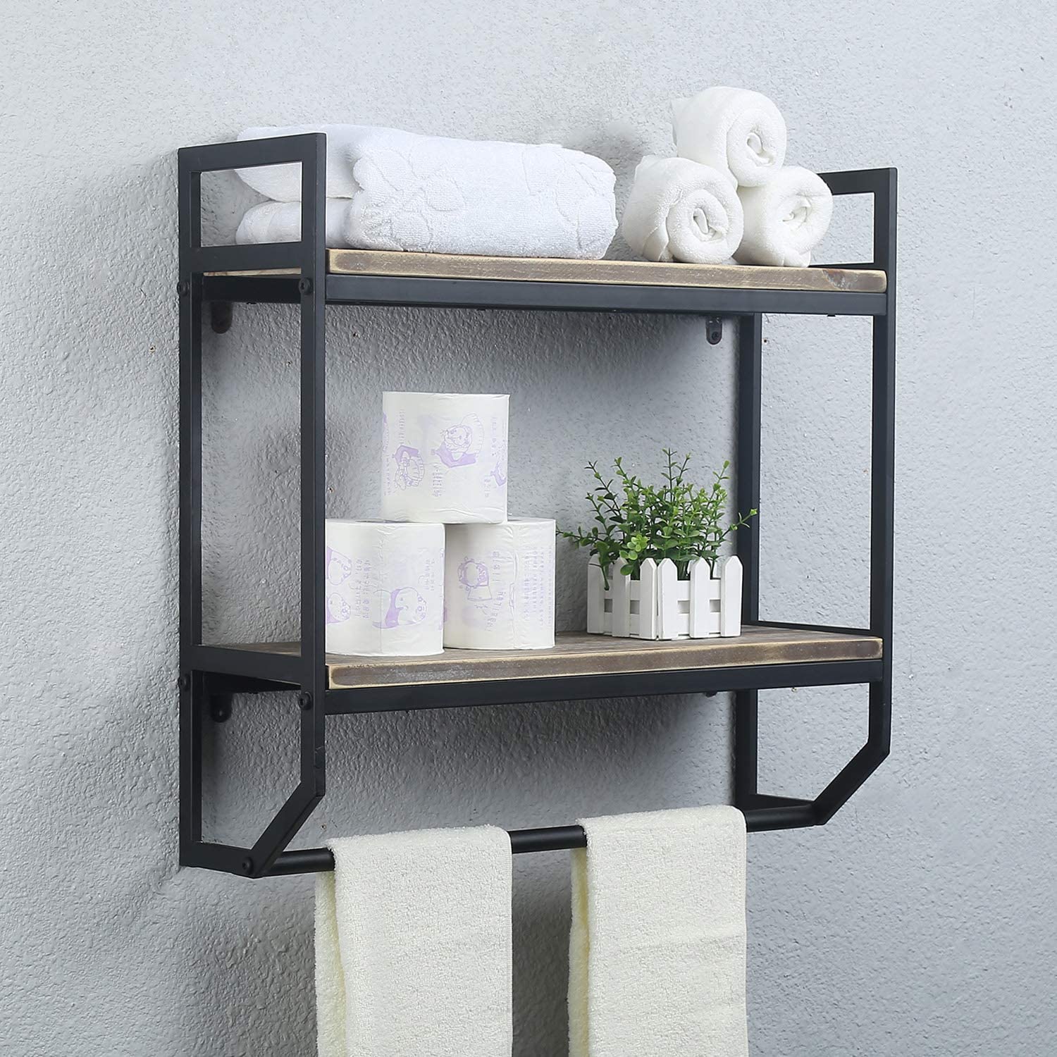 A wall-mounted black metal and wood storage shelf holding towels and toilet paper rolls against a grey textured wall.