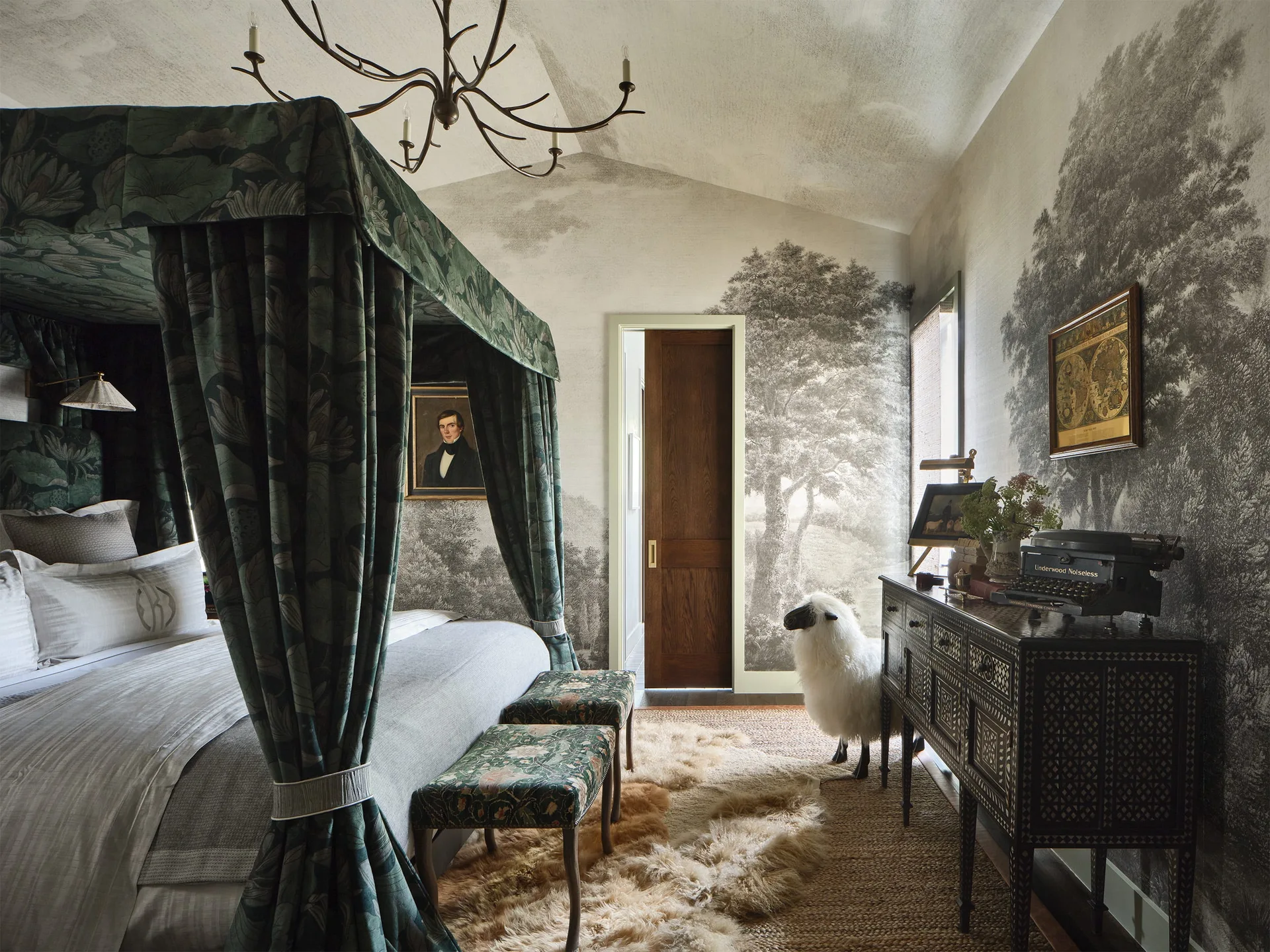 A traditional bedroom features a green patterned canopy bed, a grey monochrome forest wall mural, and an ornate wooden sideboard.