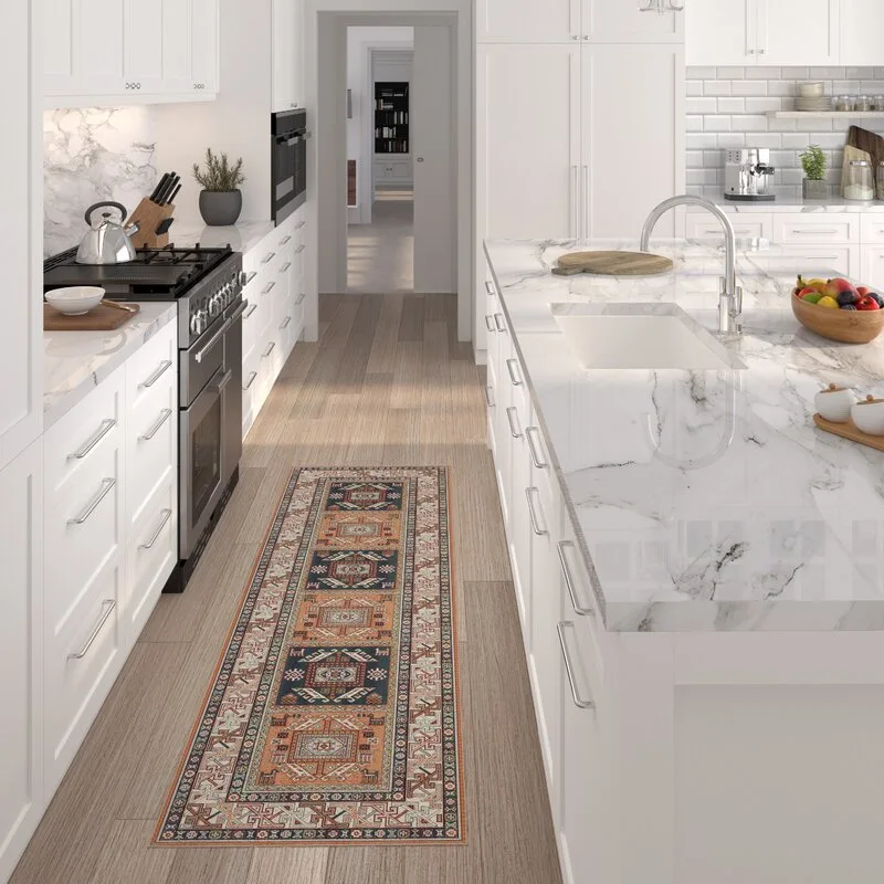 A white kitchen features a marble island, matching countertops, white shaker cabinets, and a colorful patterned runner rug on light wood flooring.