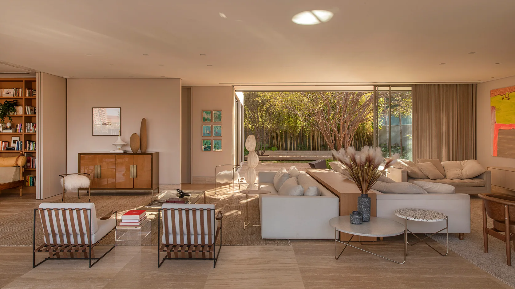 A spacious living room features cream sofas, strapped leather armchairs, and a large sliding glass door that opens to a bamboo garden.