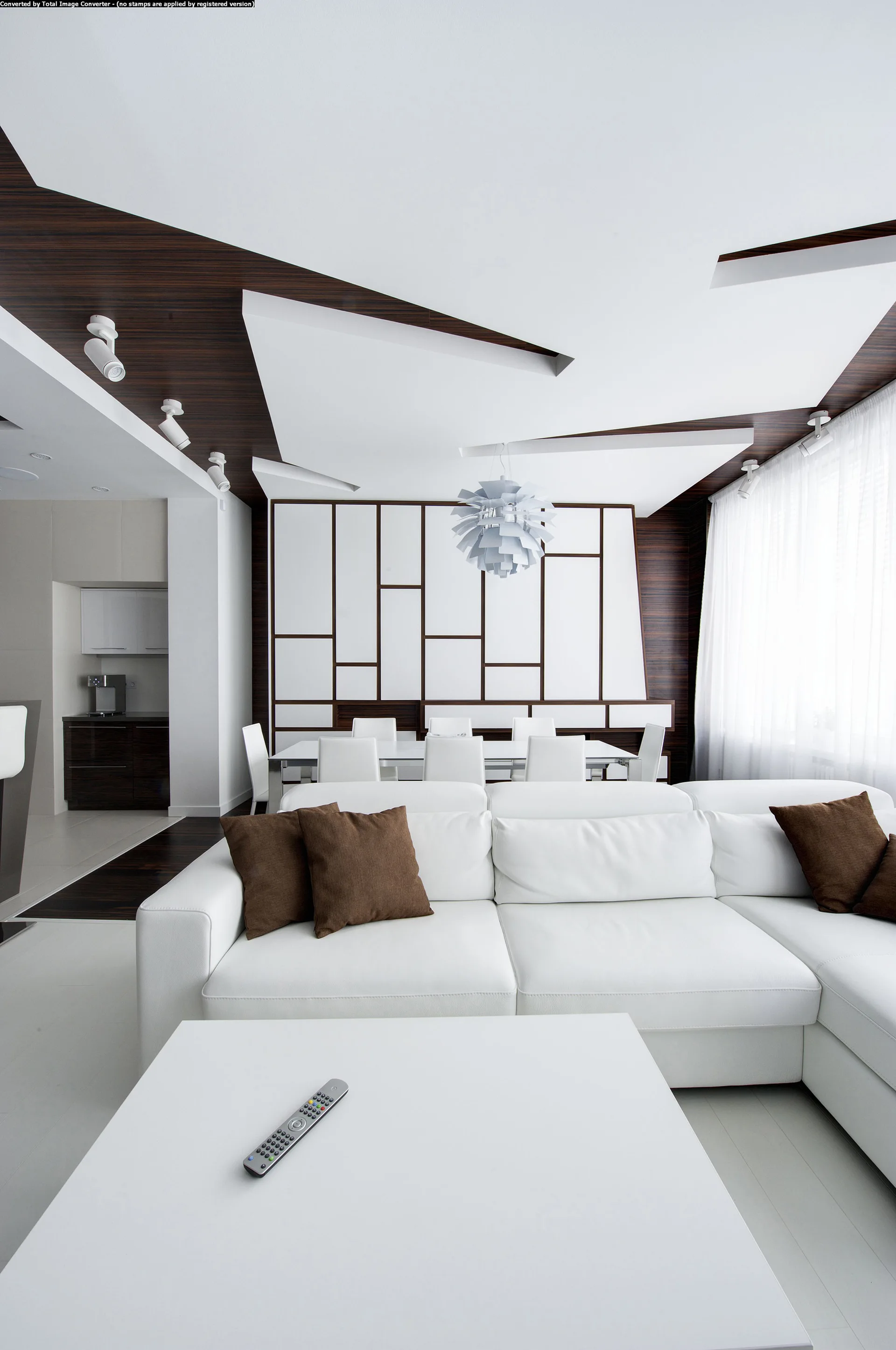 A modern living room features a white sectional sofa, a matching dining set, and distinctive geometric wood paneling on the ceiling and back wall.