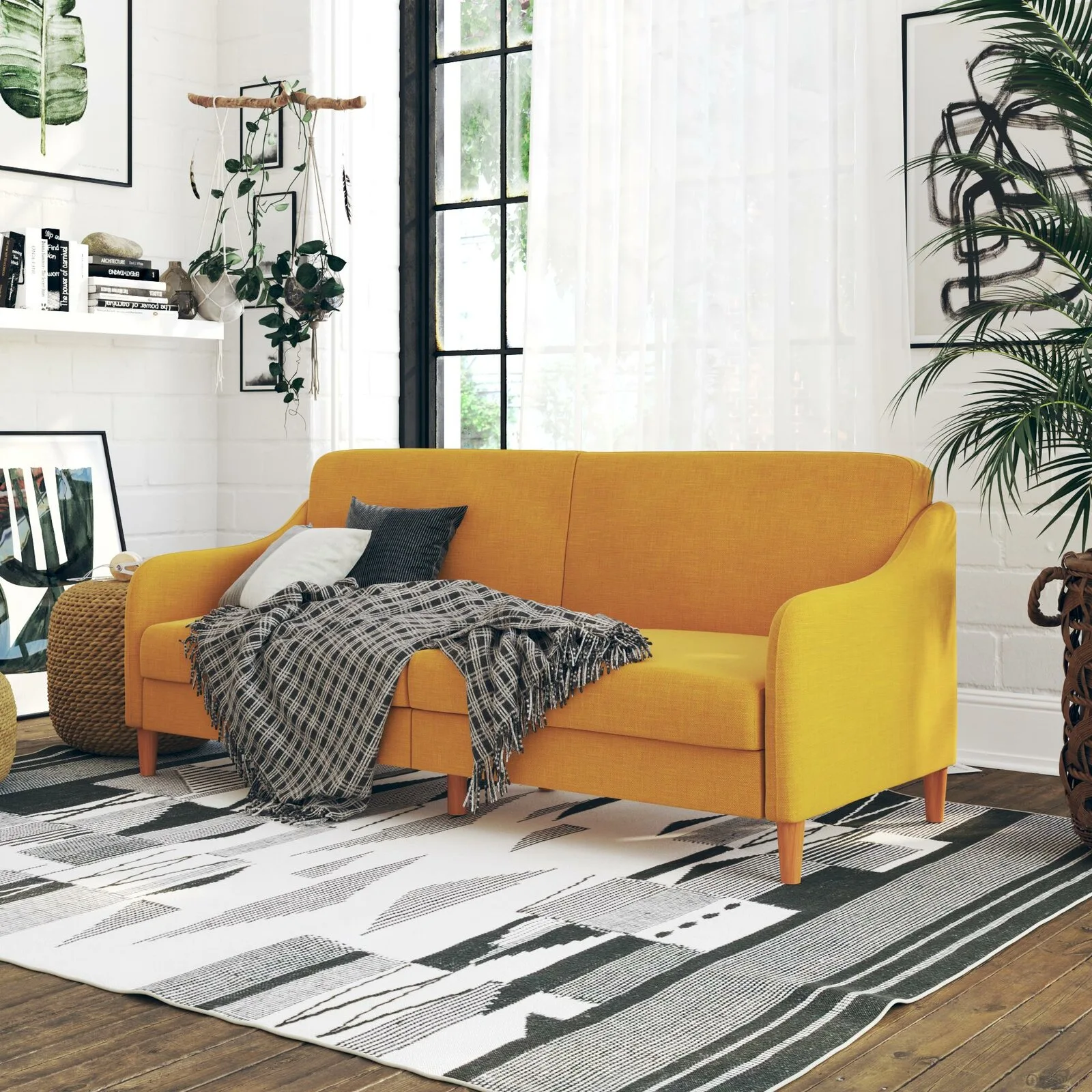 A bright yellow sofa sits on a black and white geometric rug in a living room with white painted brick walls and a large window.