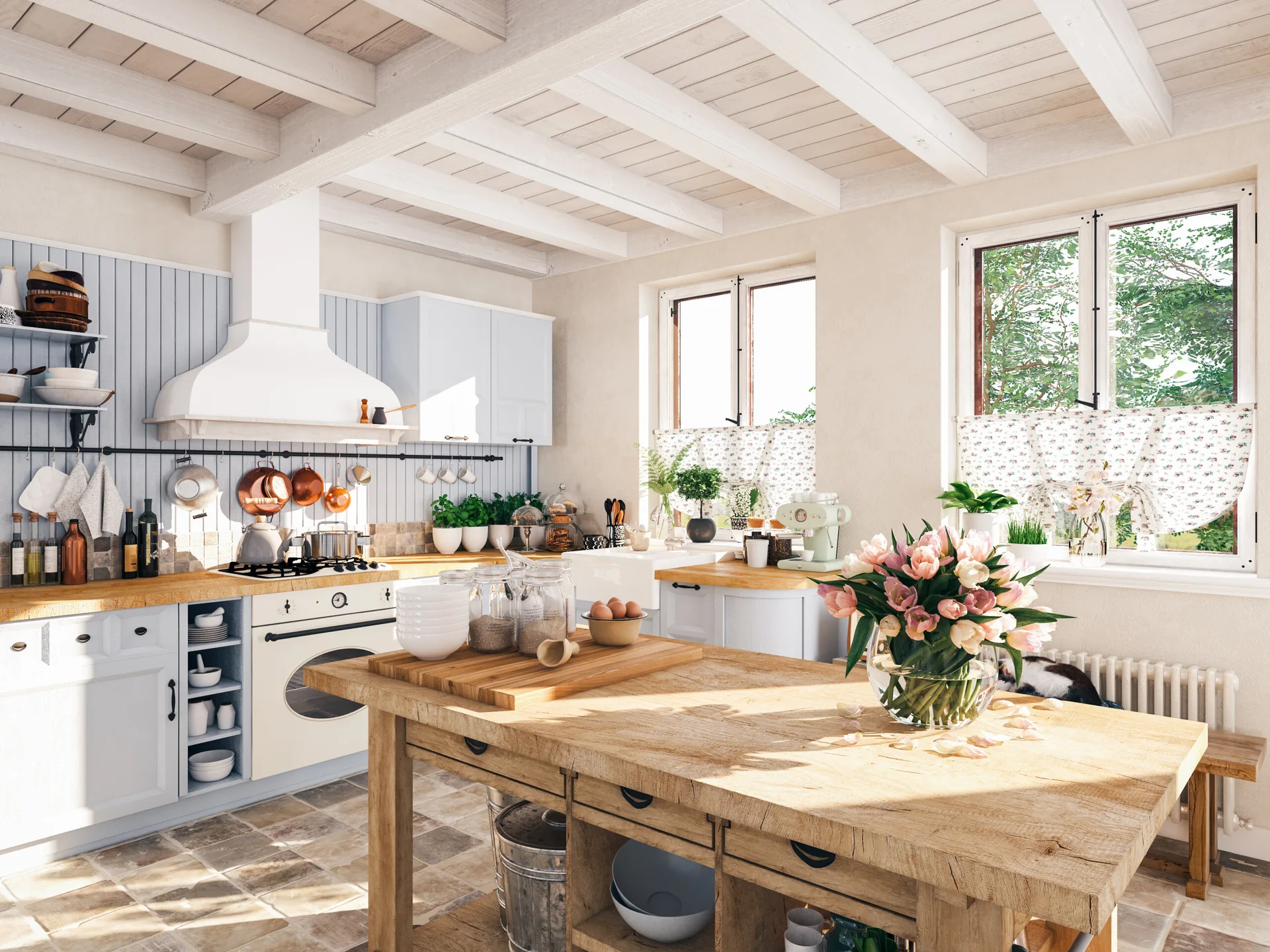 A bright cottage kitchen features light blue cabinets, a rustic wooden kitchen island, white painted ceiling beams, and copper pots hanging over the stove.