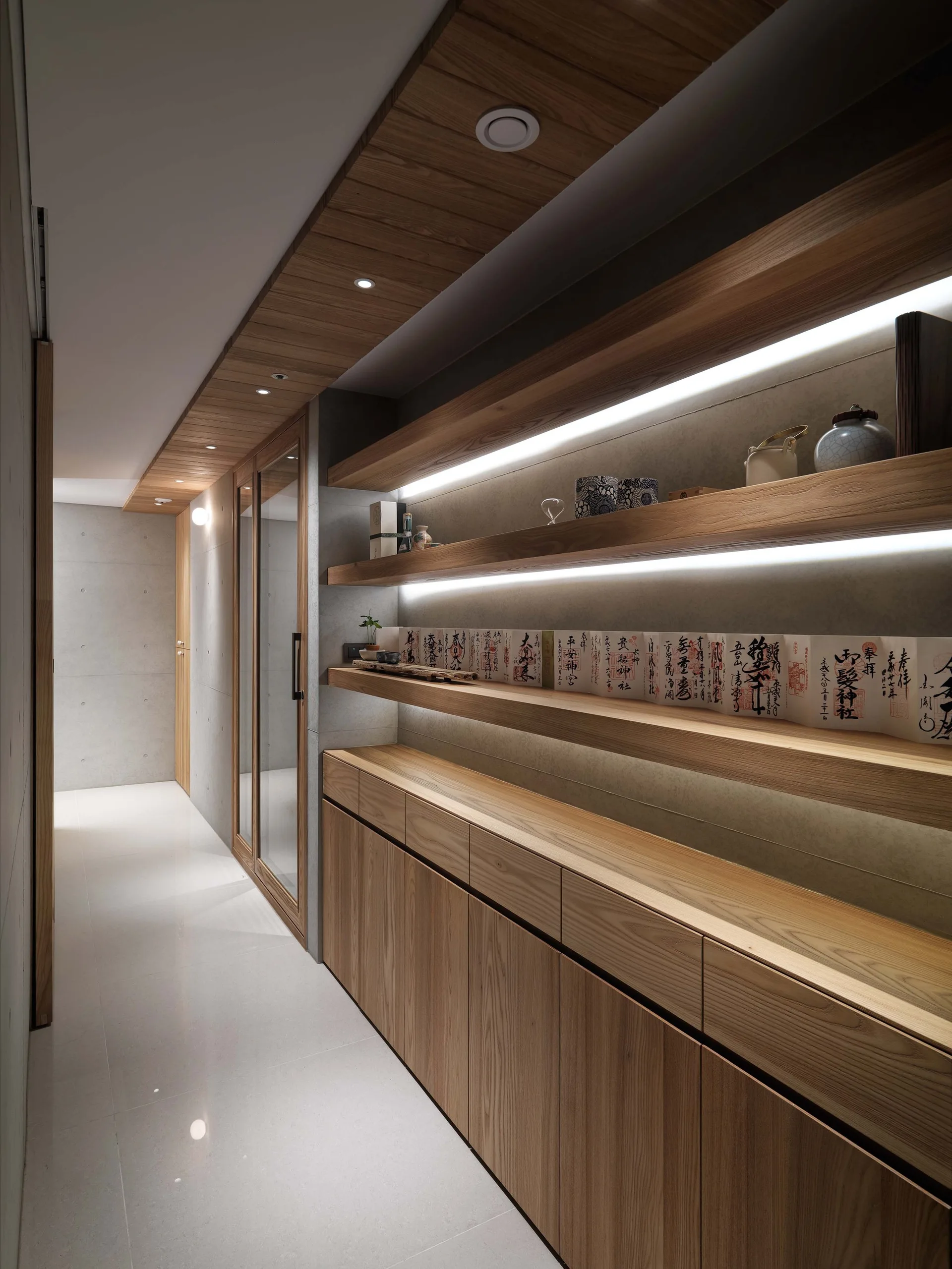 A minimalist hallway features built-in wooden lower cabinets, long floating shelves with integrated LED lighting, and grey concrete walls.