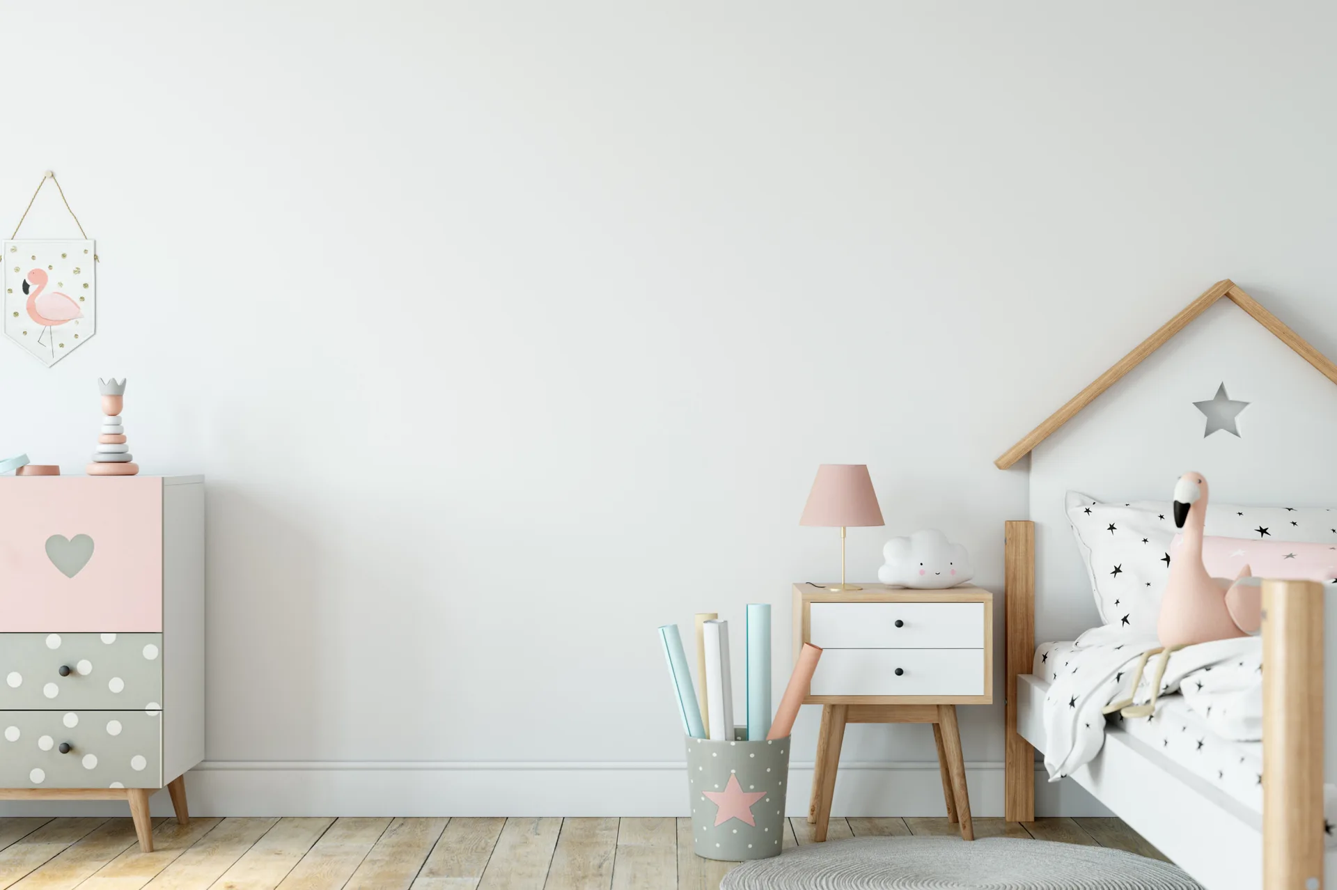 A children's bedroom features a white house-frame bed, a two-drawer nightstand, a polka dot dresser, and soft pink decor items on light wood floors.