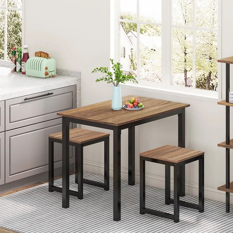 A compact wood and black metal dining table with two matching backless stools sits on a striped rug near a kitchen counter.