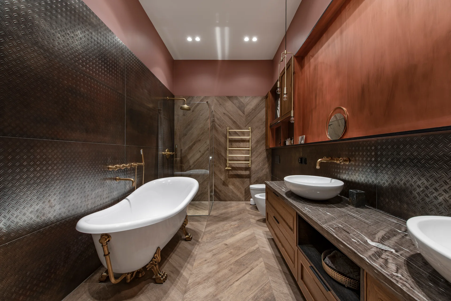 A bathroom features a white clawfoot bathtub, double wood vanity, dark metallic wall panels, and brown herringbone pattern flooring.