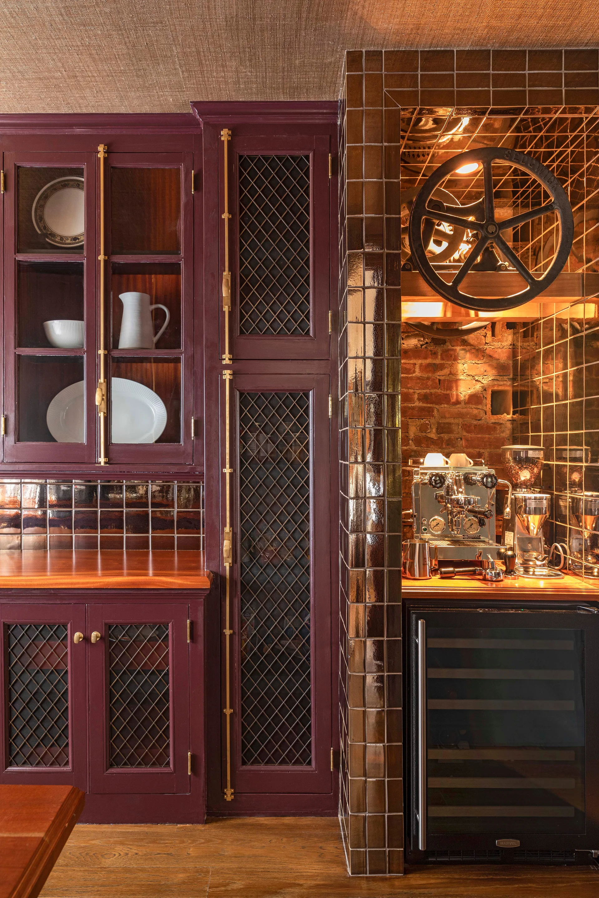Plum-colored kitchen cabinets with latticework doors flank a tiled coffee nook containing a silver espresso machine and wine cooler.