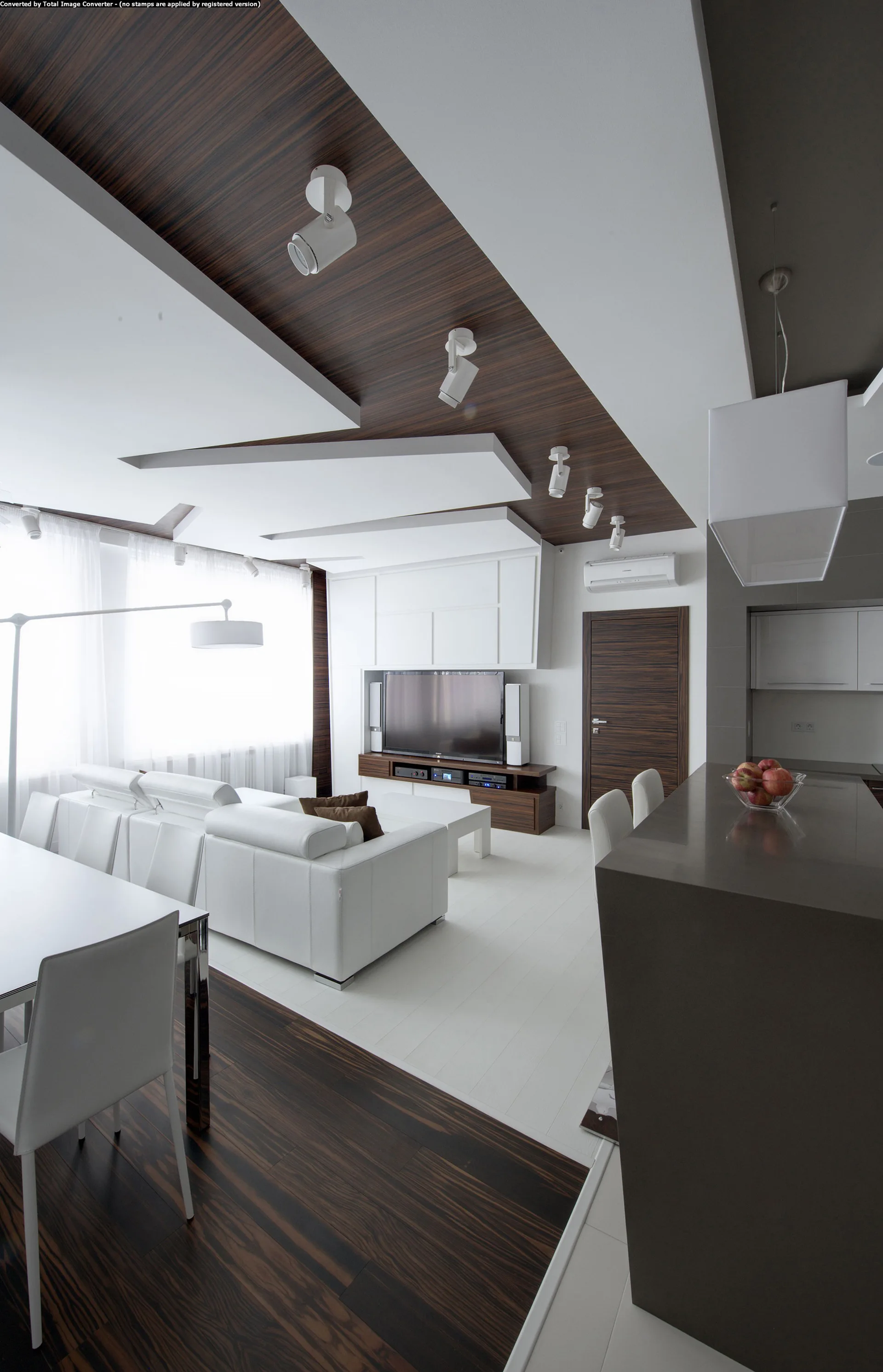 A modern open-plan living room featuring a white leather sofa, dark wood floors, and a layered ceiling with dark wood inlays and track lights.
