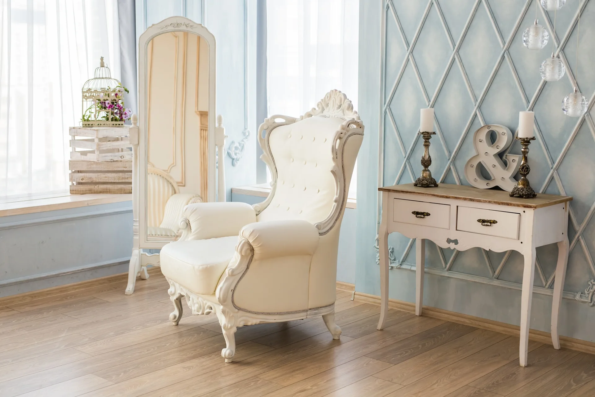 A classic light blue living room features a white tufted armchair, a matching standing floor mirror, and a small console table.