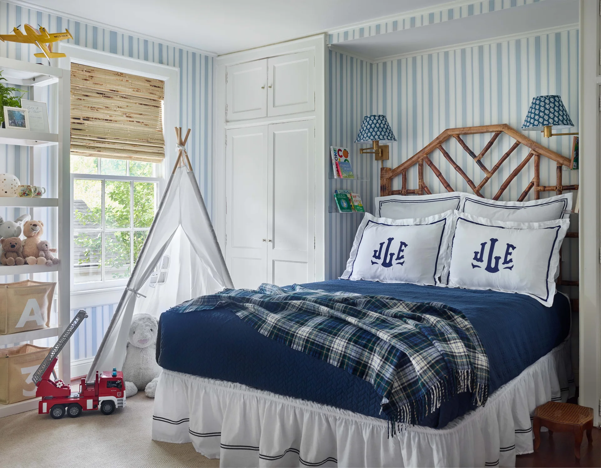 A children's bedroom features blue striped wallpaper, a bed with a rattan headboard, a white built-in closet, and a small play teepee near the window.