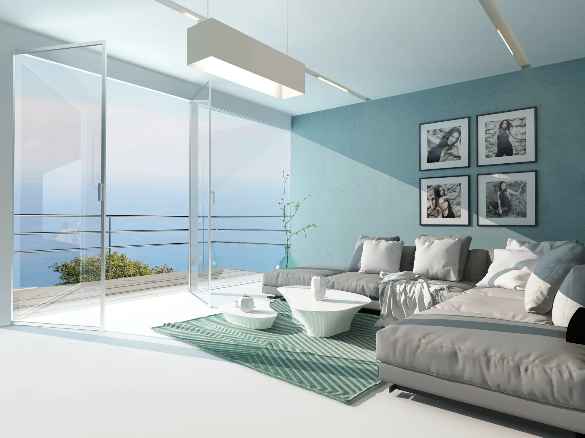 A grey sectional sofa sits on a green patterned rug in a modern living room with a teal accent wall and glass doors opening to a sea view.