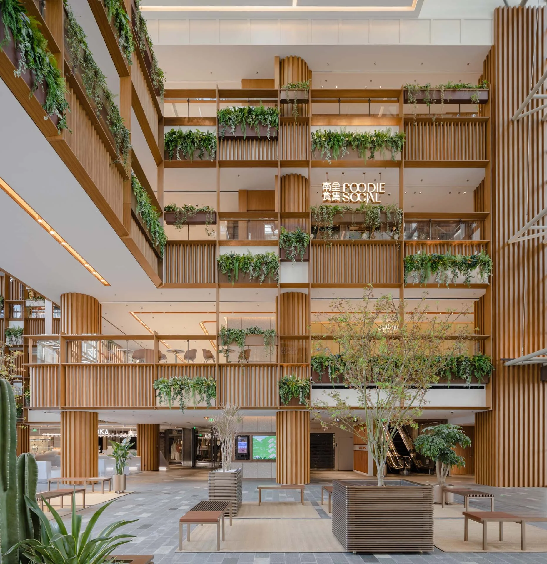 A large modern multi-level atrium with tall columns and balconies clad in vertical wooden louvers integrated with green planter boxes.