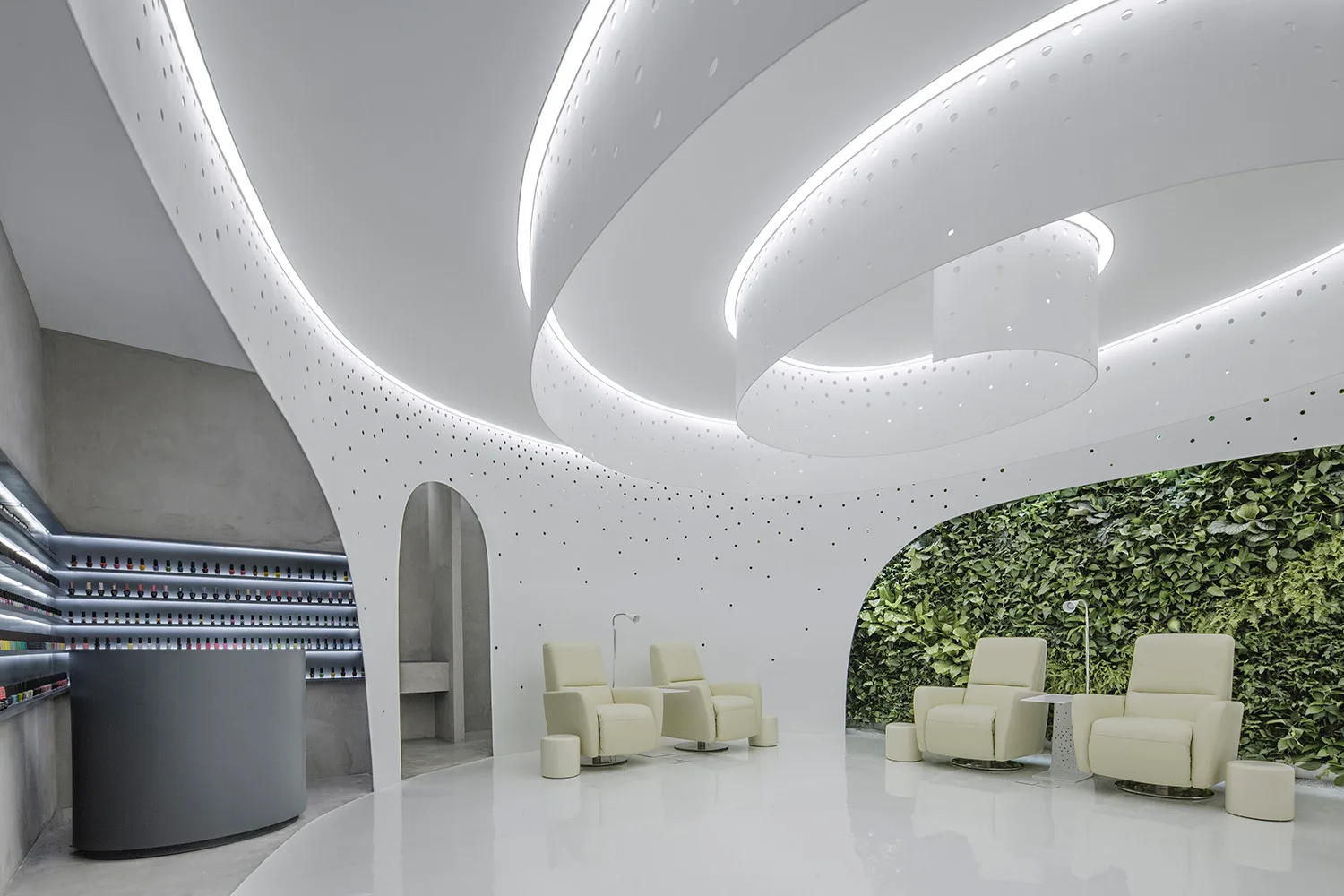 A modern wellness salon features white curved perforated walls, cream reclining chairs, a reflective glossy floor, and a vertical living wall.