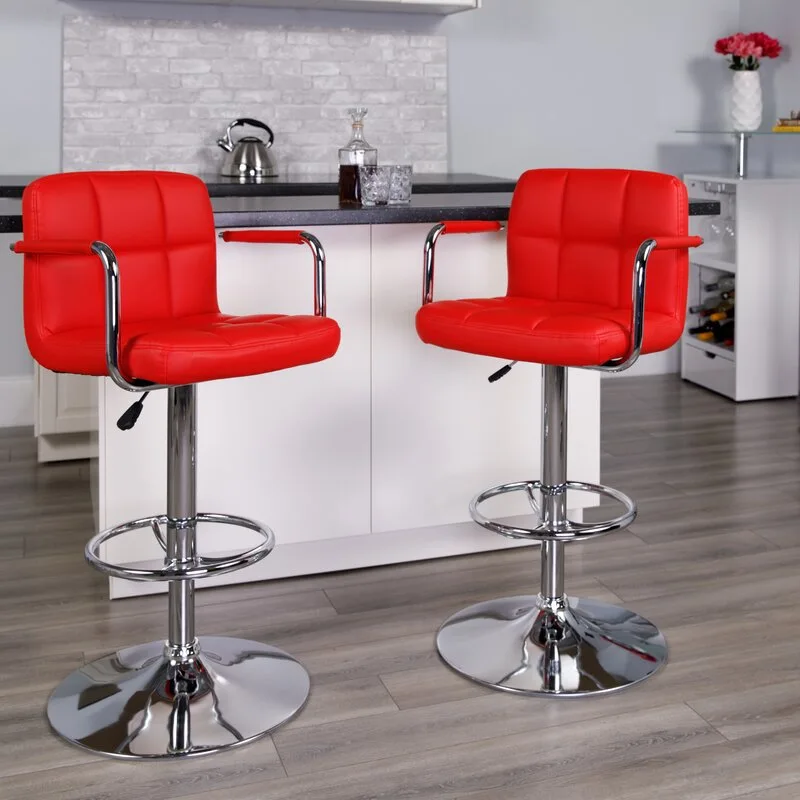 Two red faux leather swivel bar stools with chrome pedestal bases stand in front of a white kitchen counter.