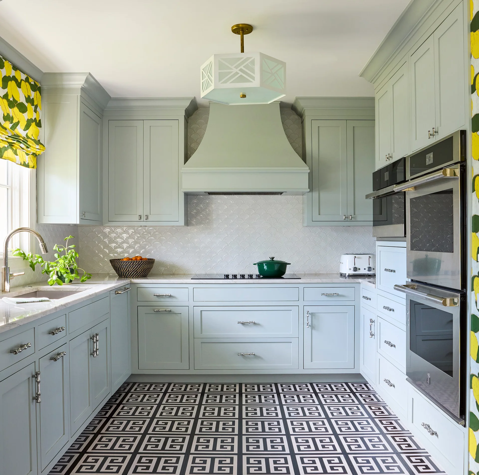 A u-shaped kitchen featuring light blue shaker cabinets, a scalloped tile backsplash, and a black and white geometric patterned floor.